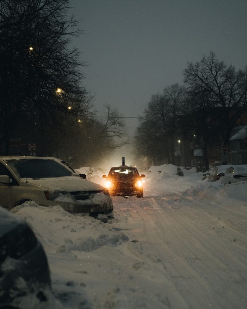 white car on snow covered road during night time